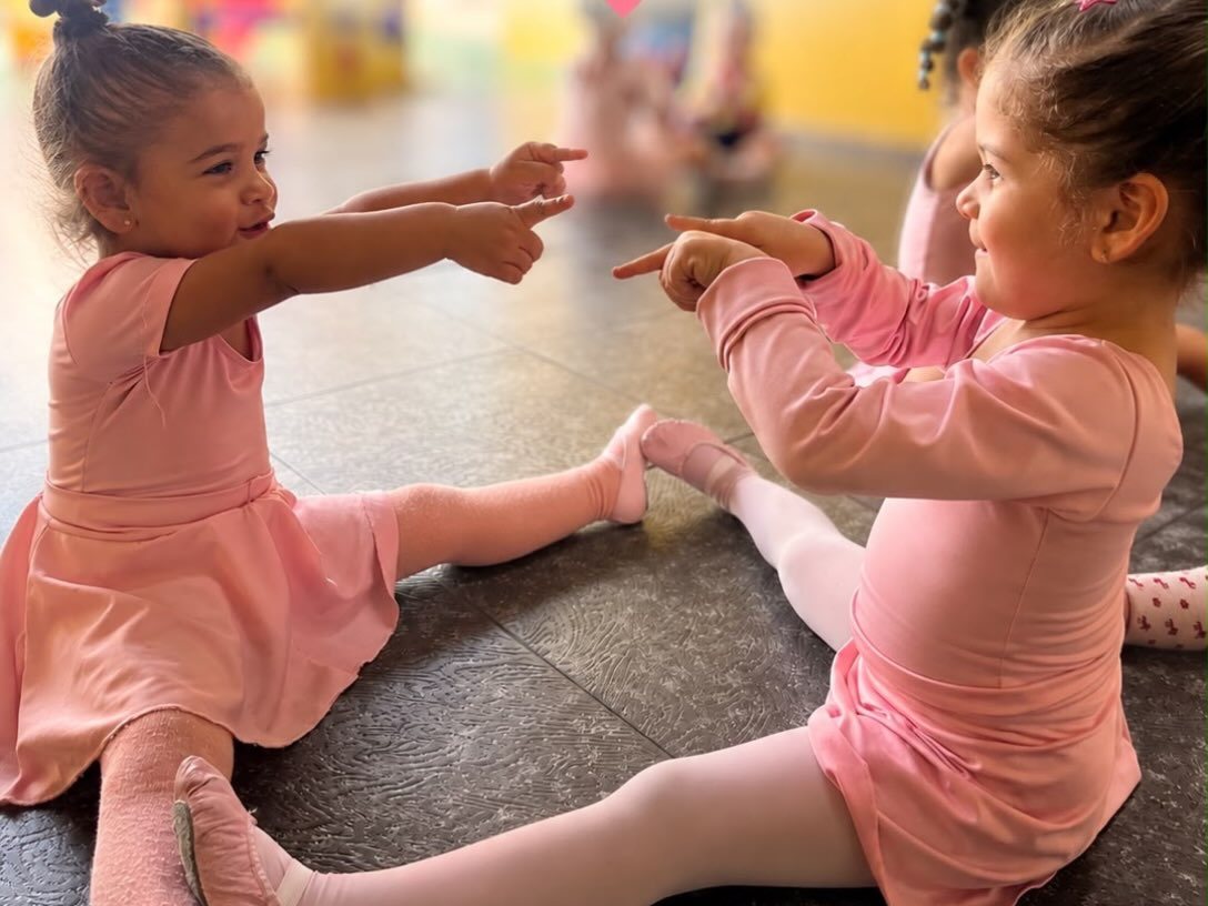 Duas alunas de collant rosa na aula de balé da escola