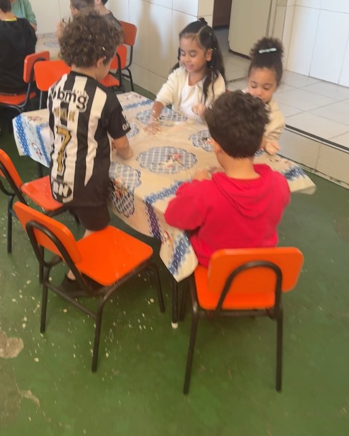 Alunos sentados às mesinhas em atividade de grupo