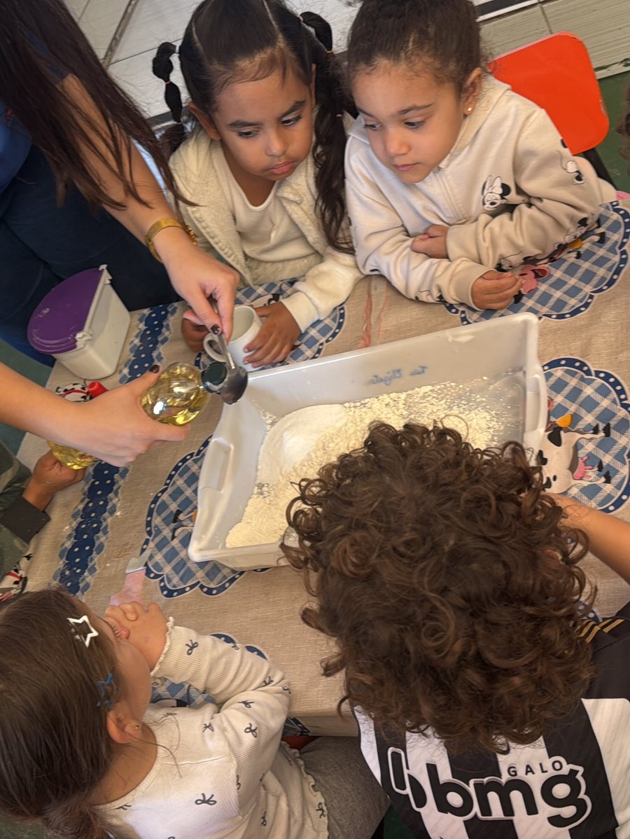 Alunas em atividade sensorial com farinha e a professora