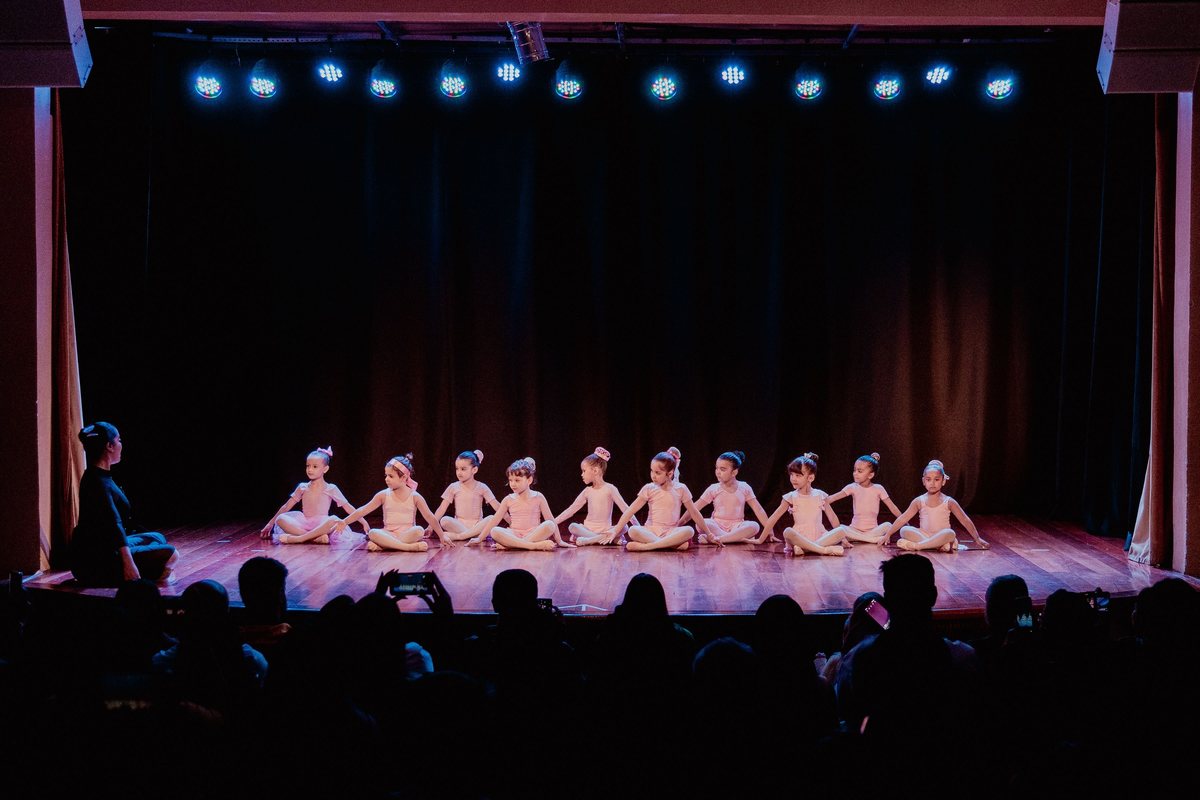 Turma de balé sentada no palco do teatro
